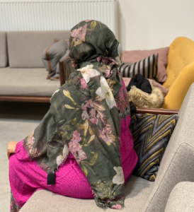 Billedet viser Maryan Noor Adan bagfra. Hun er iført en lyserød kjole og et grønt tørklæde med blomster på.